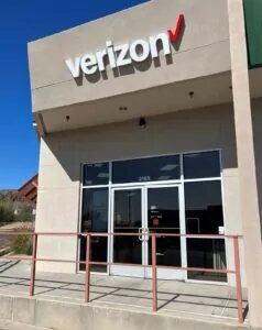 Verizon store entrance with hand rail outside building with signage above.