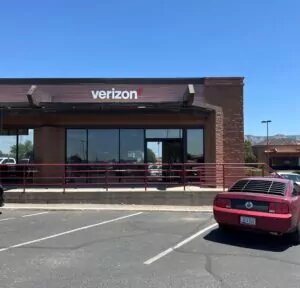 Verizon store building in dark red brick building with ADA walkway and hand rail outside entrance.