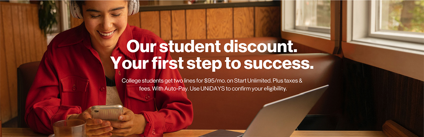 Student Discounts from Verizon Student Looking at Phone and Smiling with Laptop at Desk