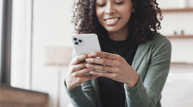 African American Woman texting on iPhone and smiling