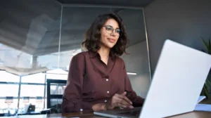 Woman working on a laptop in a modern office setting.