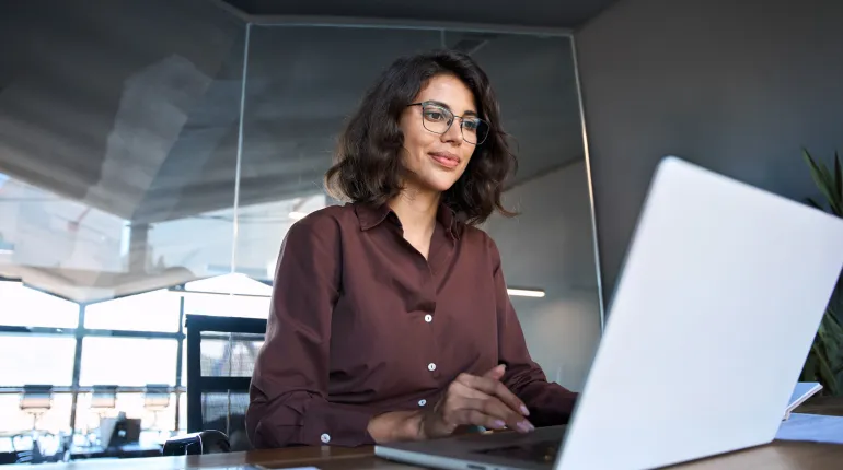 Woman working on a laptop in a modern office setting.