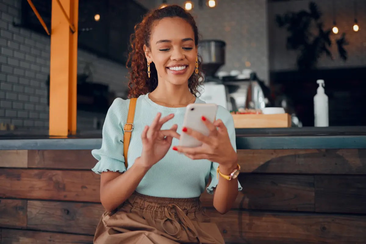 Smiling woman sitting in a café using a smartphone.