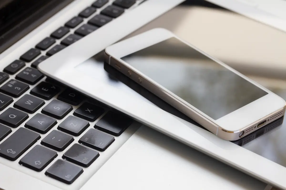 Close-up of a smartphone and tablet stacked on top of a laptop keyboard, representing modern portable digital technology.