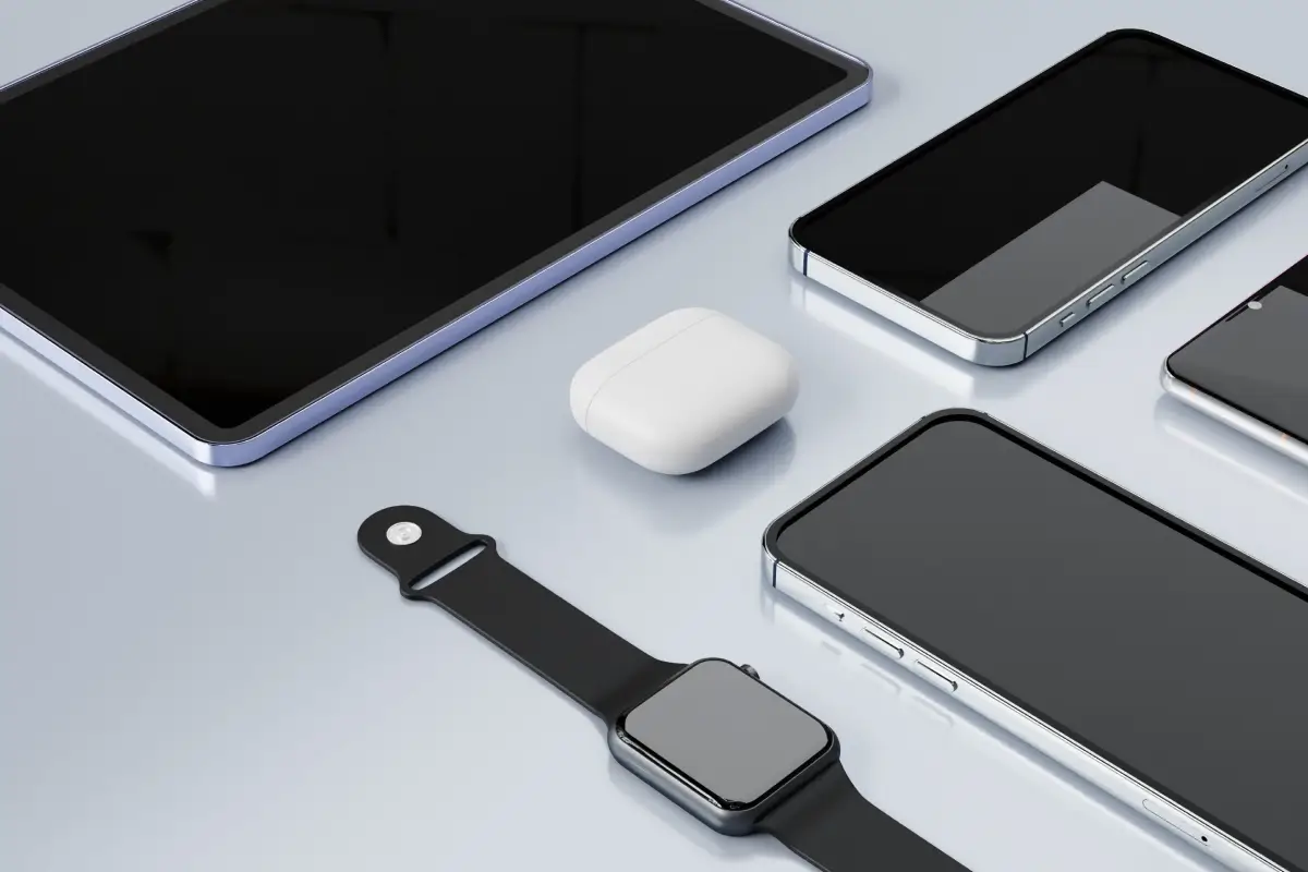 Apple devices, including an iPad, iPhones, AirPods, and an Apple Watch arranged on a reflective surface.
