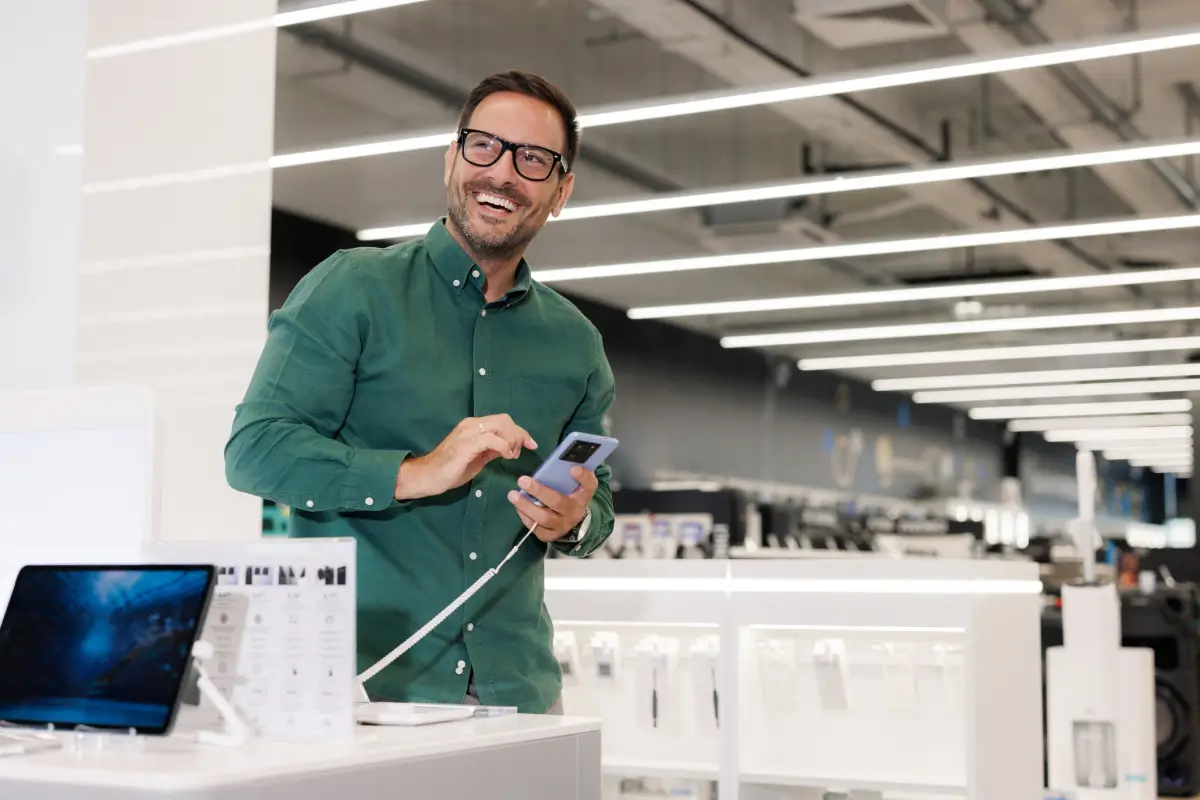A man using a cell phone in a retail store environment.