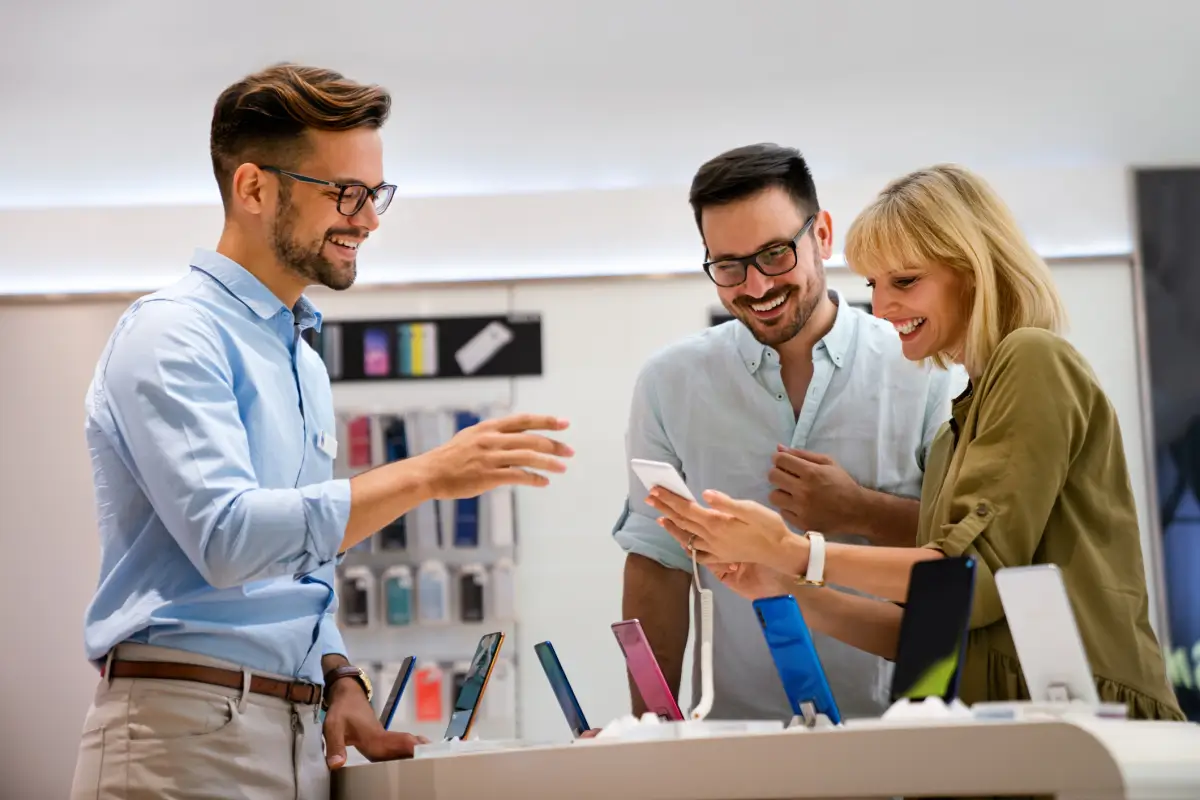 Customers examining smartphones with a sales associate in a retail store.