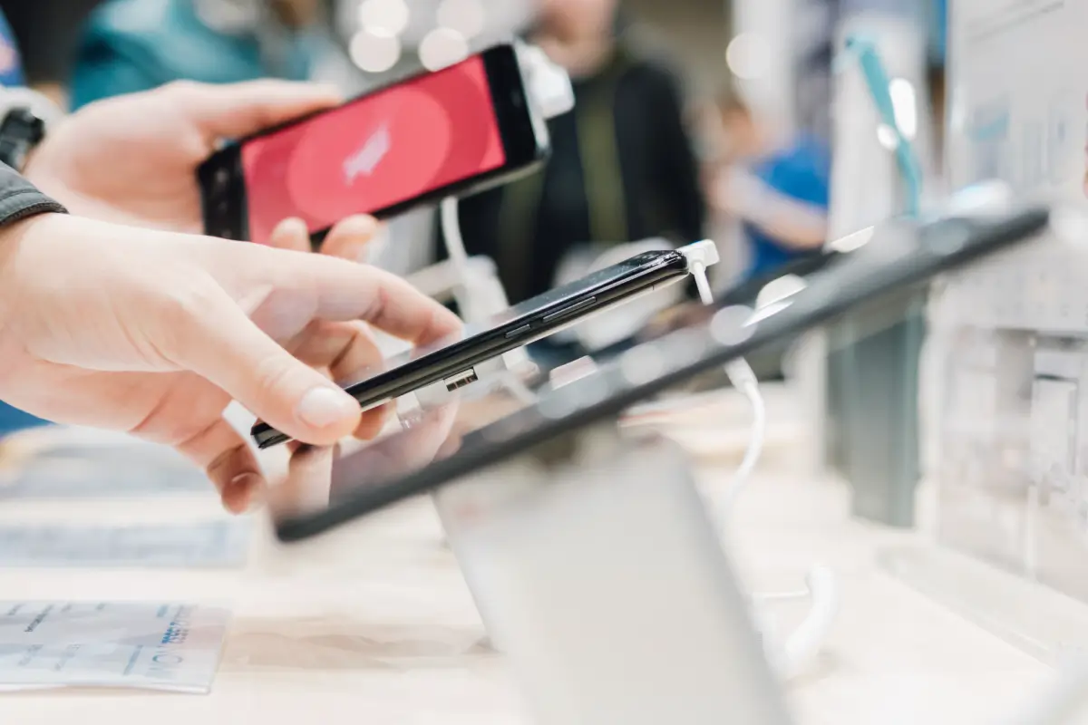Customers interacting with smartphones displayed on a retail counter.