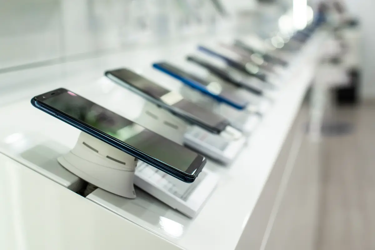 Row of smartphones on display in a brightly lit electronics store.