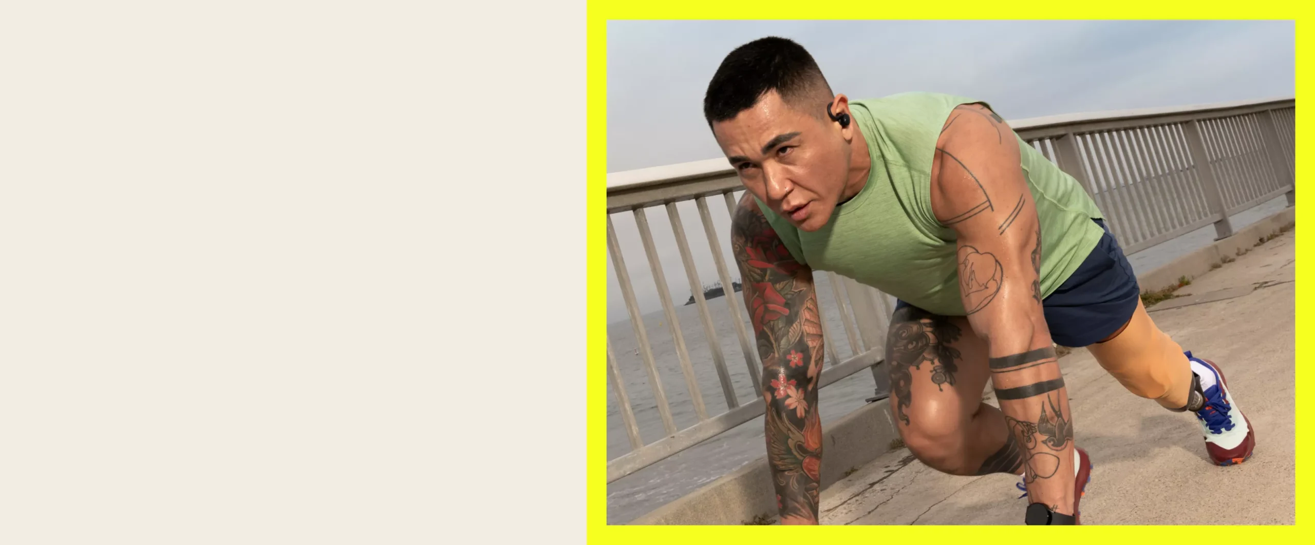 A runner in wireless earbuds crouched at a starting position on a seaside boardwalk